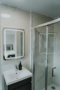een badkamer met douche, wastafel en spiegel bij Urban Luxury in Colnbrook