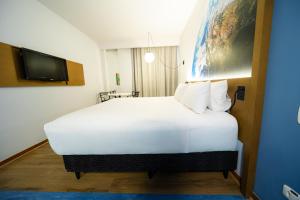 a large white bed in a room with a tv at Hotel Euro Suite Curitiba Batel By Nacional Inn in Curitiba