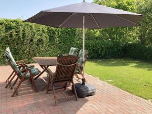 Una mesa y sillas con una sombrilla en un patio. en Holiday home with 3 bedrooms, en Norddeich