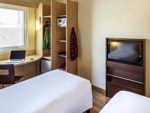 a room with a bed and a desk and a television at ibis Porto Alegre Moinhos de Vento in Porto Alegre