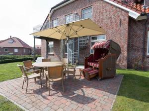un tavolo e sedie con un ombrellone in un patio di Manslagt - Greetsiel a Greetsiel