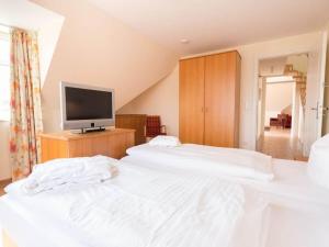 2 letti bianchi in una camera con televisore di Manslagt - Greetsiel a Greetsiel