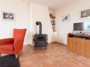 un soggiorno con camino, sedia e TV di Manslagt - Greetsiel a Greetsiel