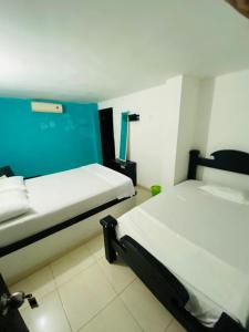 une chambre avec deux lits et un mur bleu dans l'établissement Hostal Santa Maria City, à Santa Marta