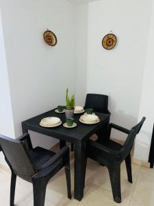 une table et des chaises noires avec des assiettes et une plante sur celle-ci, dans l'établissement Hostal Santa Maria City, à Santa Marta