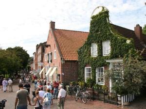 een groep mensen die door een straat voor een gebouw lopen bij Twixlum - Greetsiel in Greetsiel