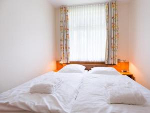 een slaapkamer met een groot wit bed met een raam bij Twixlum - Greetsiel in Greetsiel