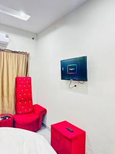 a room with two red chairs and a tv on a wall at Flat in wah cantt in Wāh
