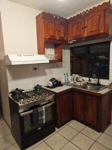 a kitchen with wooden cabinets and a stove top oven at The Carnival Residence at Queens Park Savannah in Valencia Village +10 photos