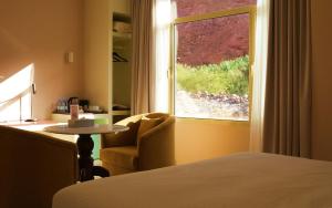 a room with a bed and a table and a window at Wadi Sader in Al-ʿUla