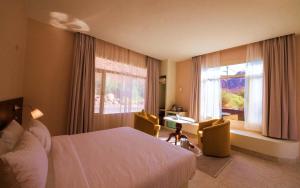 a hotel room with a bed and two chairs and a window at Wadi Sader in Al-ʿUla