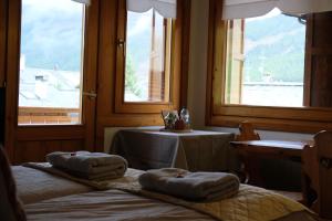 2 letti in una camera con due finestre e un tavolo di Appartamento Rin, Livigno a Livigno