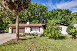 a white house with a palm tree in the yard at Bring Your Boat! Canal-Front Tavares Home with Dock in Tavares