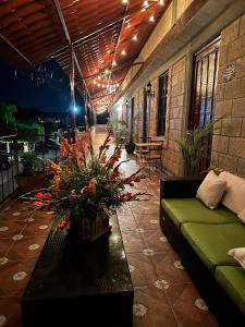 a patio with a green couch and flowers on it at Hotel Posada Rancho Los Laureles in El Rosario Xochitiopan +10 photos