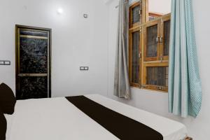 a bedroom with a white bed and a window at Hotel O Naman Guest House in Gorakhpur