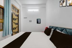 a bedroom with a white bed and a blue couch at Hotel O Naman Guest House in Gorakhpur