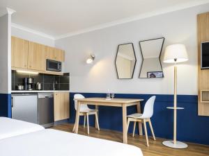 a small kitchen with a table and chairs in a room at Aparthotel Adagio La Défense Kléber in Courbevoie +51 photos