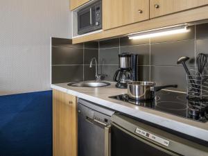 a kitchen with a sink and a stove top oven at Aparthotel Adagio La Défense Kléber in Courbevoie +42 photos