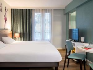 a hotel room with a bed and a desk and a tv at Aparthotel Adagio Paris Montmartre in Paris +22 photos
