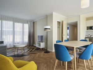 a dining room with a table and blue chairs at Aparthotel Adagio Porte de Versailles in Issy-les-Moulineaux +74 photos