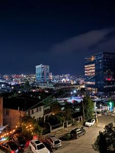 Una ciudad de noche con coches estacionados en un estacionamiento en Teo Apartment, en Pristina