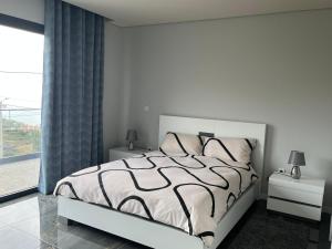 a white bedroom with a bed and a large window at Villa Bacana Oasis in Estreito da Calheta