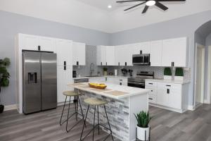 Una cocina con gabinetes blancos y un refrigerador de acero inoxidable. en The Blue House, en Hitchcock