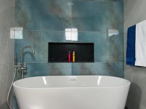 a white tub in a bathroom with a tile wall at Villa Bacana Oasis in Estreito da Calheta