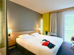 a hotel room with a large bed and a window at ibis Styles Nantes Reze Aéroport in Rezé