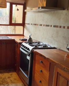 y cocina con fogones y hervidor de agua. en Juella cabaña, en Tilcara