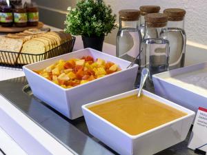 a bowl of fruit and a bowl of honey on a counter at ibis budget Torun in Toruń