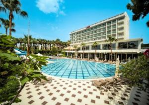 a hotel with a swimming pool in front of a building at Sentido Lycus Beach Hotel in Alanya +11 photos