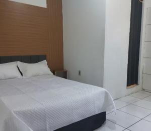 a bedroom with a white bed and a window at Quarto confortável COP30 in Belém