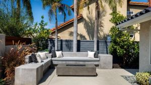 a patio with a couch and palm trees at Spanish-Inspired Mission Viejo Home with Courtyard Firepit Backyard Dining Casa Cordero by AvantStay in Galivan
