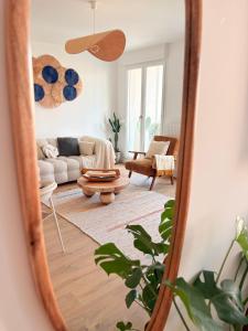 ein Wohnzimmer mit einem Sofa und einem Tisch im Spiegel in der Unterkunft Appartement F3 Neuf Vue sur la Seine avec Parking Gratuit Proche Paris Tour Eiffel & Disney in Cormeilles-en-Parisis