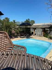 a pool with a chair and an umbrella next to it at Chalé com Piscina e Natureza Primavera Rosa in Penha