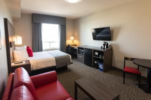 a hotel room with a bed and a tv and a couch at Kanata Whitecourt in Whitecourt