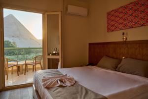 1 dormitorio con cama y vistas a las pirámides en Beit Khufu Pyramid Hotel, en El Cairo