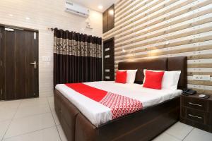 a bedroom with a large bed with red pillows at Hotel O Max in Jalandhar