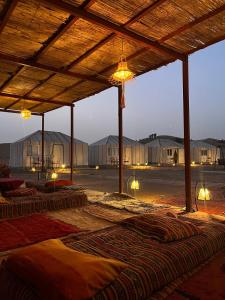 Una fila de colchones bajo una estructura de madera con luces. en farah desert camp, en Oulad Driss