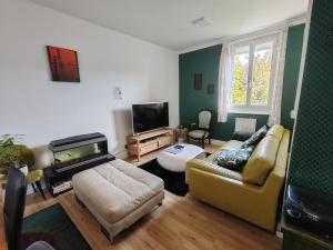 a living room with a couch and a flat screen tv at Le Grand Coquet in Besançon