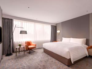a hotel room with a large bed and a chair at Pullman Shanghai Central in Shanghai