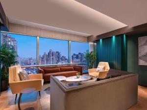 a living room with a couch and a large window at Pullman Shanghai Central - In XinTianDi & Yu Garden Area in Shanghai