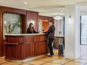 a man standing at a bar in a hotel lobby at Hotel Faubourg Galant Paris - Handwritten Collection in Paris
