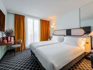 a hotel room with a large bed and a desk at Hotel Faubourg Galant Paris - Handwritten Collection in Paris +124 photos
