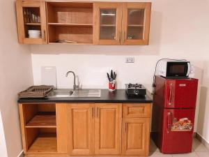 uma cozinha com um lavatório e um frigorífico vermelho em Bosco em Accra