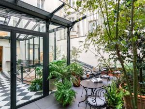 an outdoor patio with tables and chairs and plants at Hotel Faubourg Galant Paris - Handwritten Collection in Paris