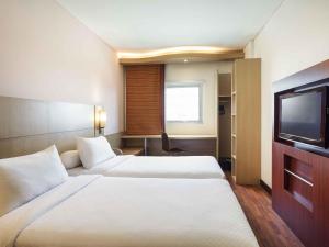 a hotel room with two beds and a flat screen tv at Ibis Balikpapan in Balikpapan