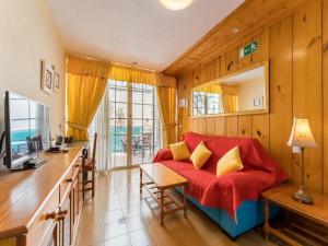 ein Wohnzimmer mit einem roten Sofa und einem Tisch in der Unterkunft Luxury apartment with garden views in El Médano