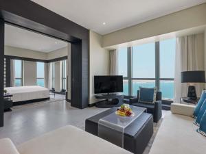 un salon avec un canapé, un lit et une télévision dans l'établissement Sofitel Abu Dhabi Corniche, à Abu Dhabi